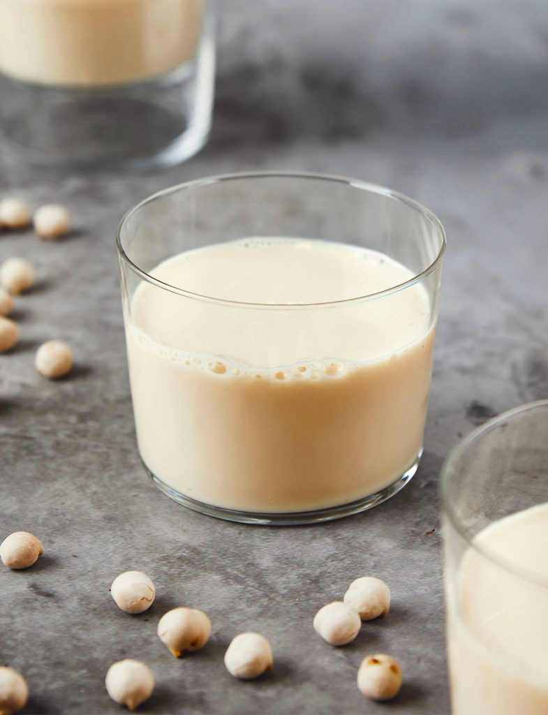 Bevande proteiche: bicchiere di bevanda proteica vegetale con legumi sullo sfondo