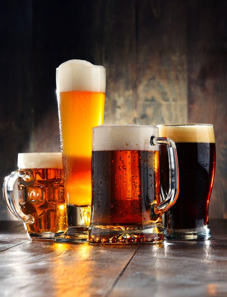 Birre chiare e scure servite in bicchieri e boccali, con schiuma cremosa