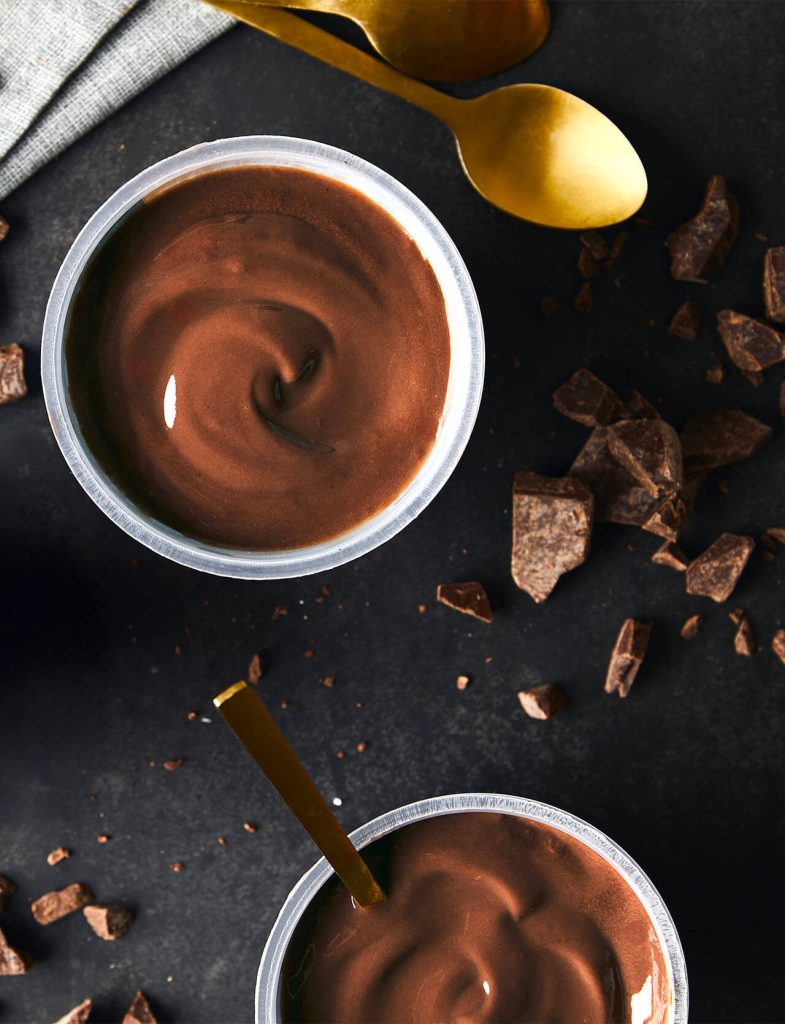 Budini e yogurt proteici: coppette di budino proteico al cioccolato con cucchiai dorati