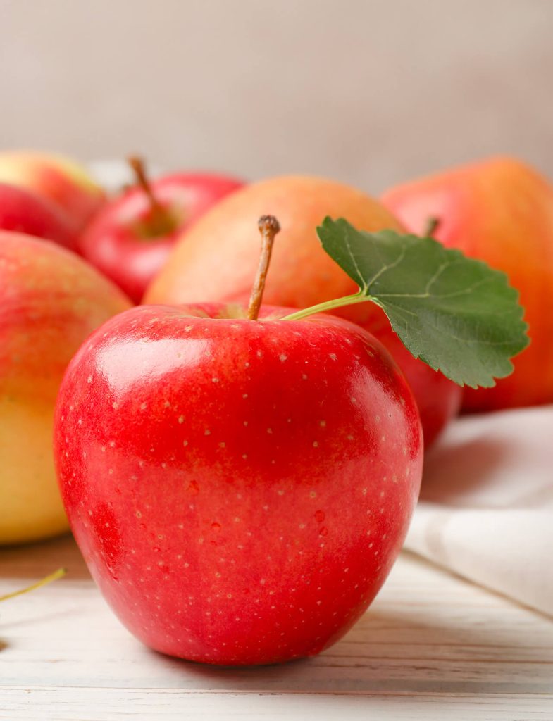 Mele rosse e assortimento di frutta fresca di stagione come kiwi, agrumi e avocado