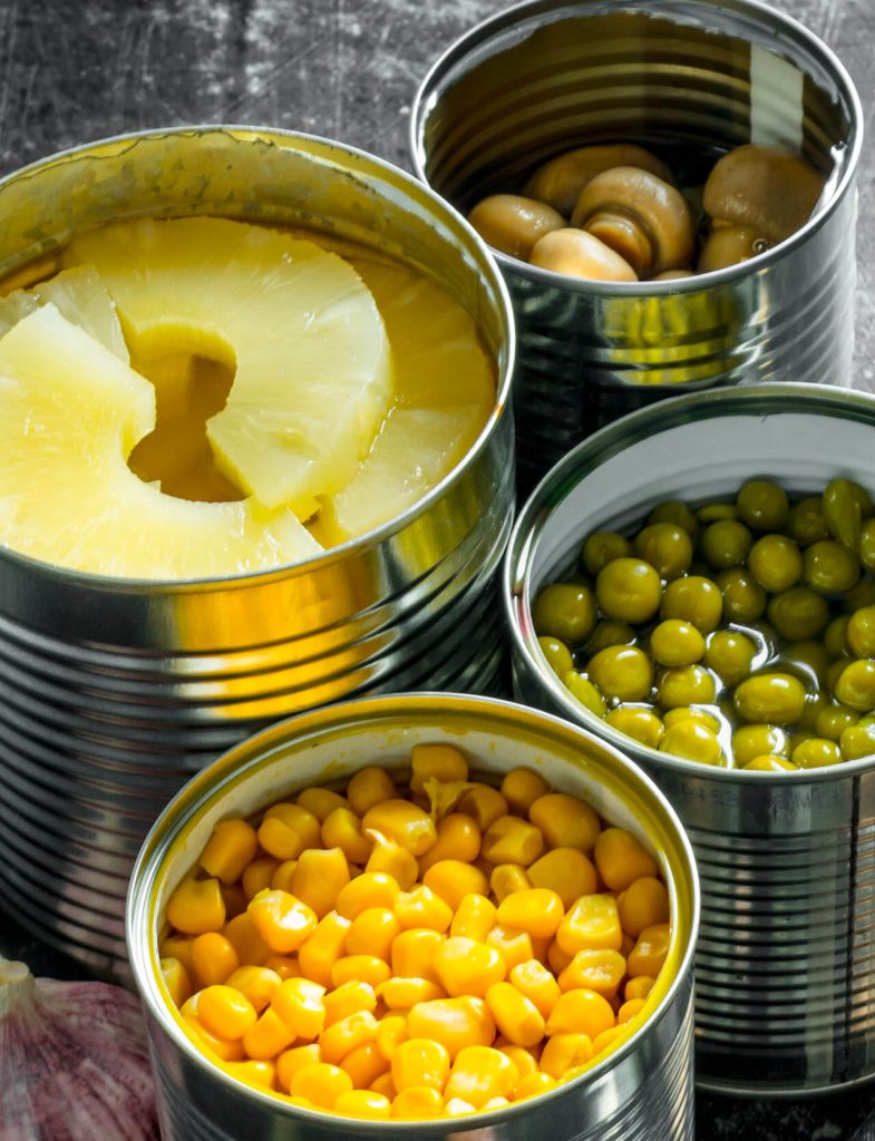 Prodotti in scatola come mais, piselli, funghi e frutta al naturale