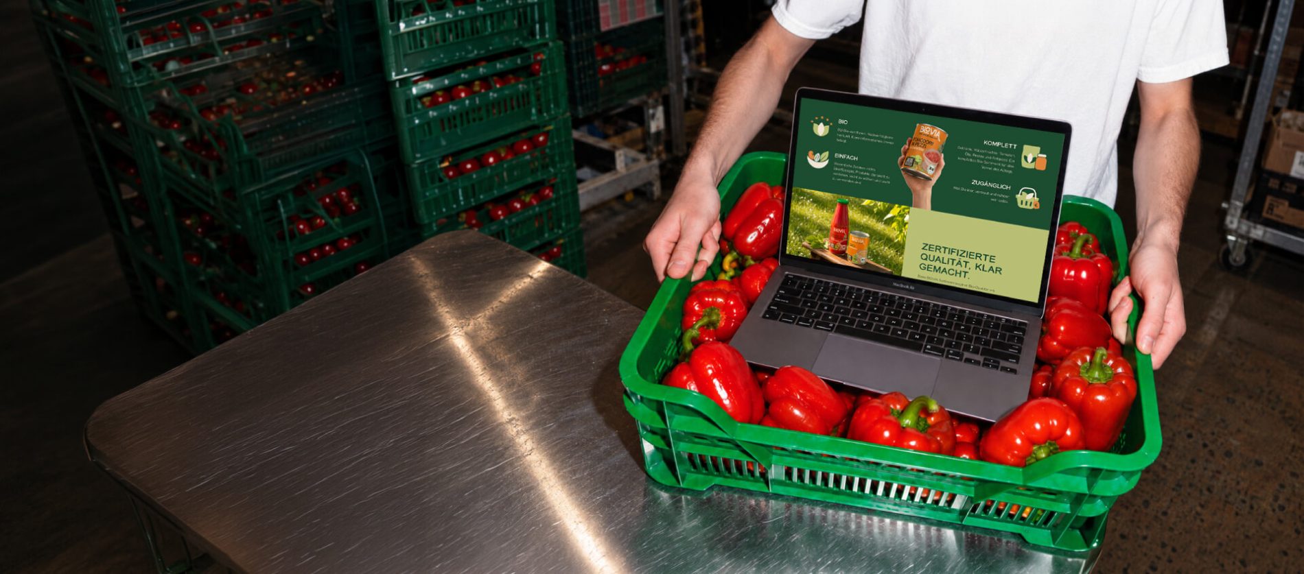bioviafood.de on a laptop in a crate of red peppers, with BIOVIA logo and the line «Organic, now online»