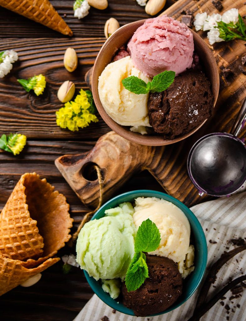Gelati assortiti in coppette e coni, gusti frutta, cioccolato e crema