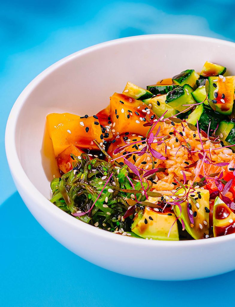Bowl di poke con riso, avocado, verdure fresche e salsa etnica al sesamo.