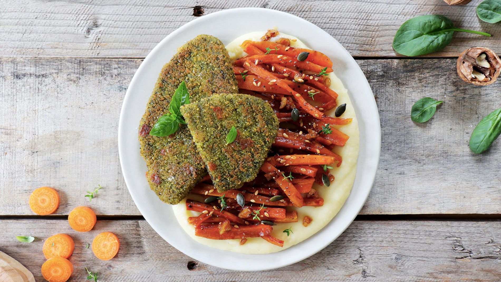 Filetti Vegamo agli spinaci e formaggio serviti con carote glassate e purè di patate su piatto chiaro.